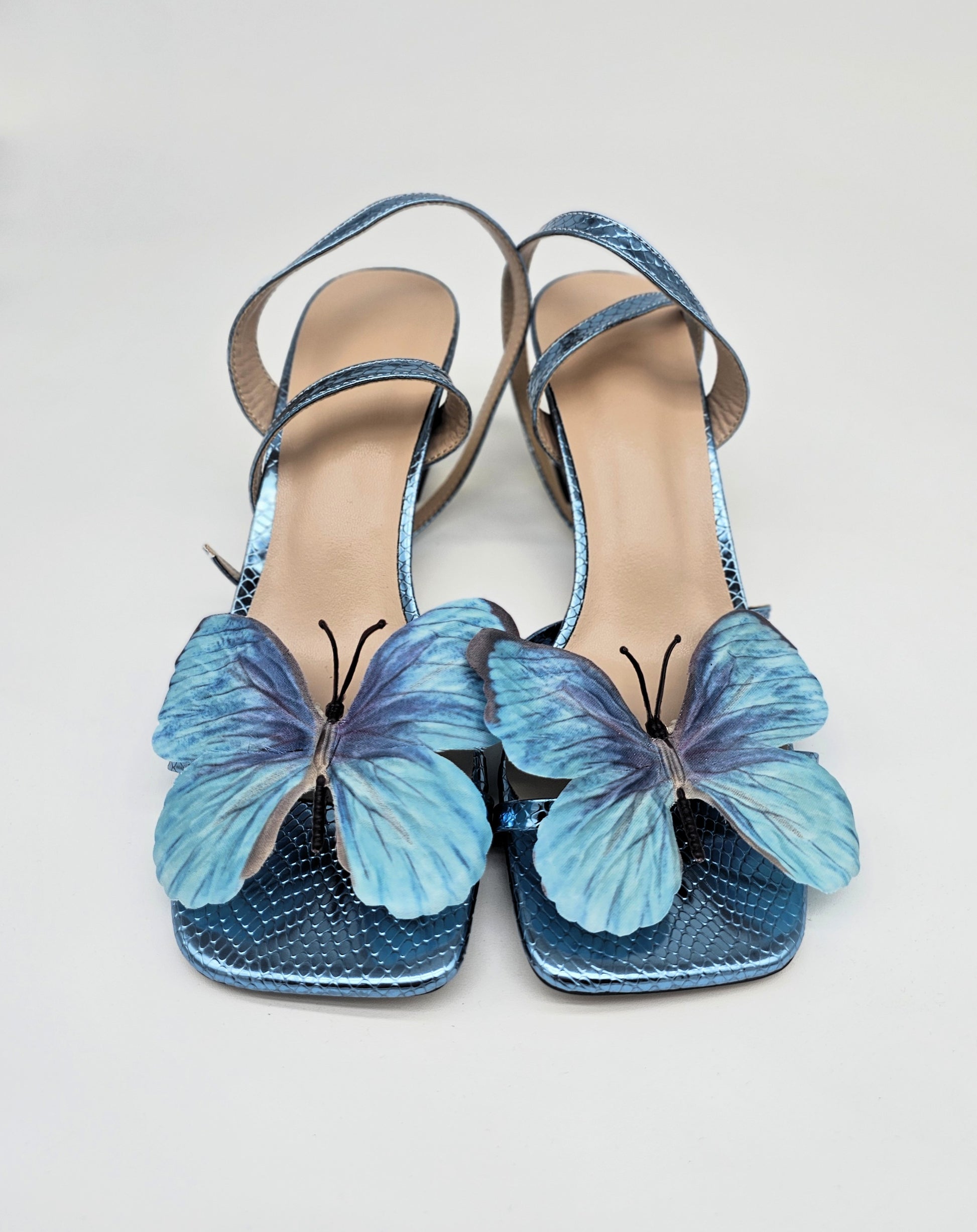 Metallic blue strappy heels with handcrafted butterfly detail, comfortable women’s sandals.