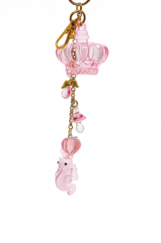 Cute pink keychain featuring a crown charm, glass lampwork seahorse, and decorative pendants on gold-plated steel.