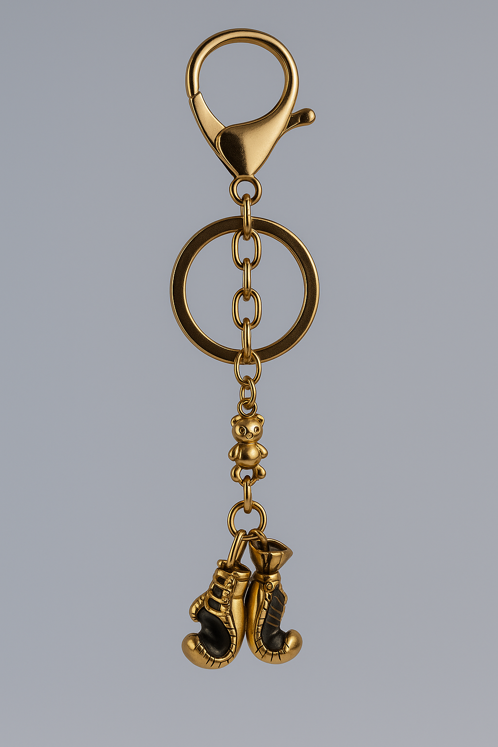 Gold keychain with boxing glove charms on a gray background