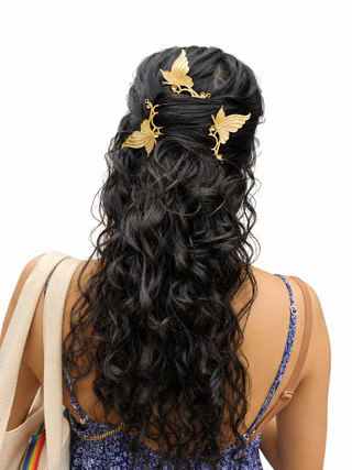 Woman with long, wavy black hair adorned with gold hair accessories on a white background