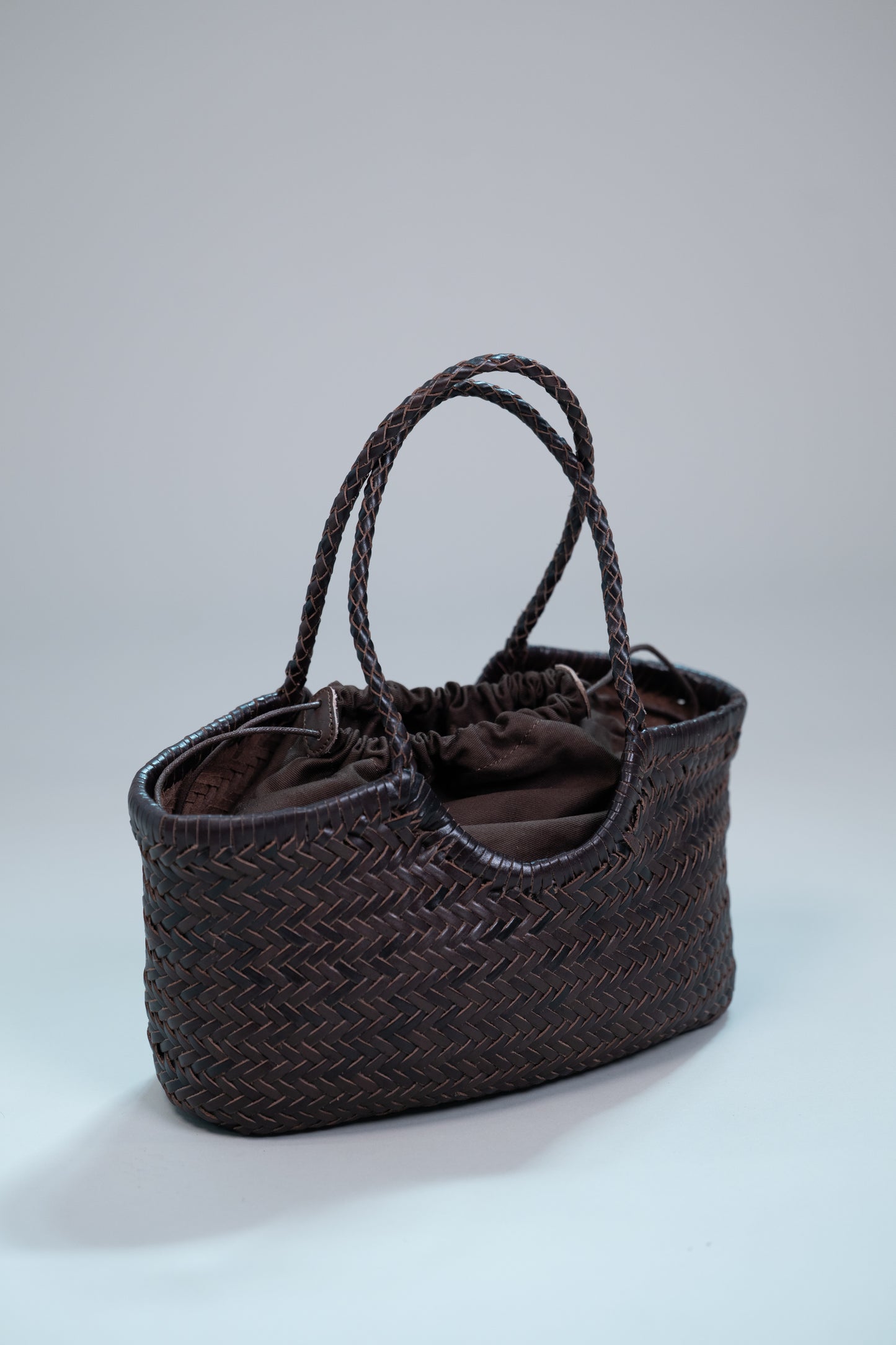 handwoven brown leather tote with braided handles and drawstring lining