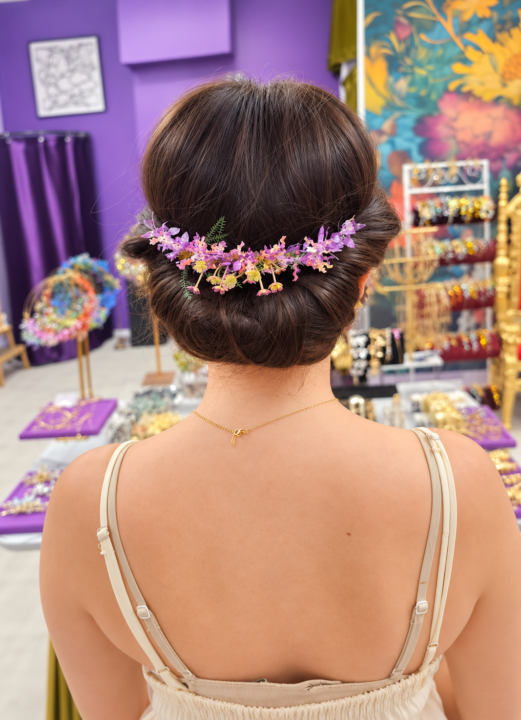 Woman wearing a purple floral Alice band at the back of a low bun, styled as an elegant statement hair accessory for weddings and events.