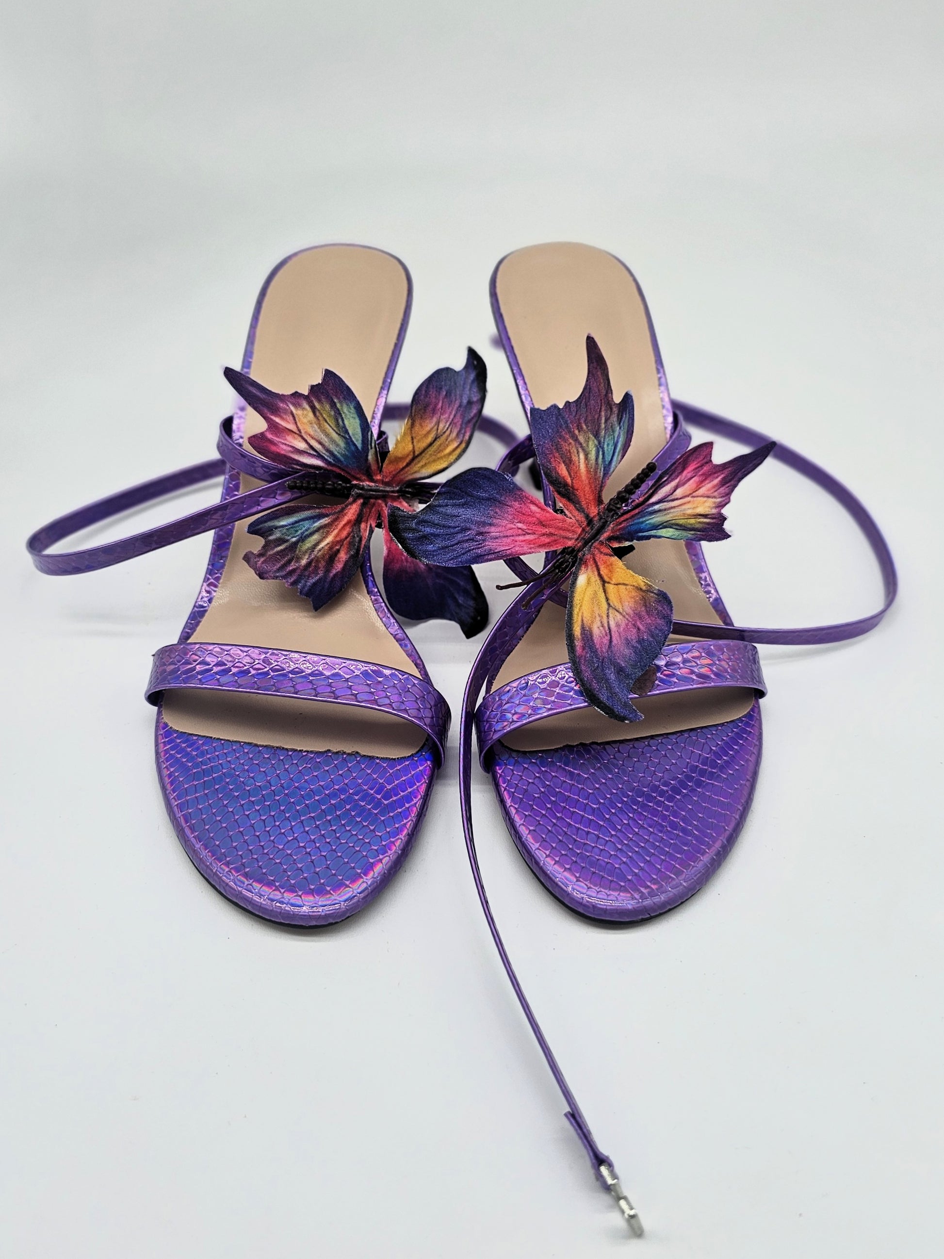Purple strappy heels with cushioned sole and handcrafted rainbow butterfly detail, stylish women’s statement sandals.