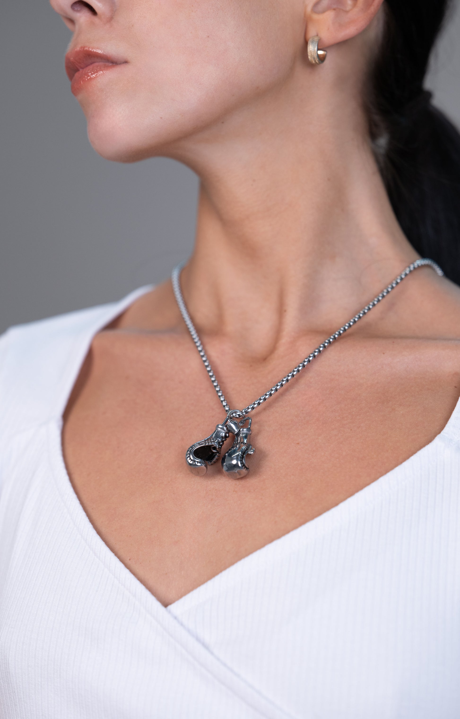 gold ball-chain necklace with two boxing-glove charms—one gold and one black-and-gold—worn at the collarbone