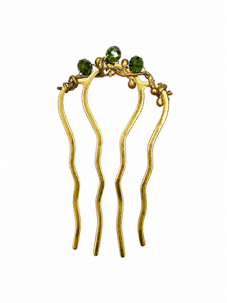 Gold hair comb with green stones on a white background